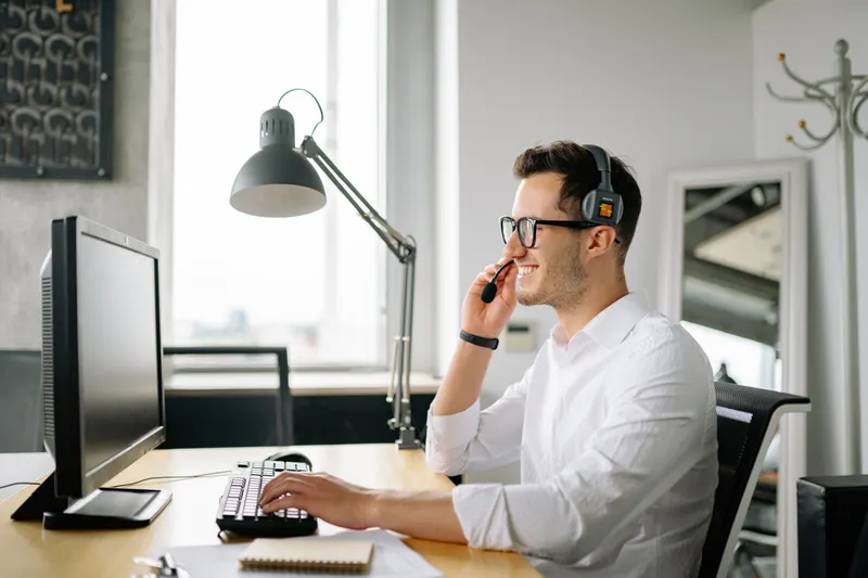 Customer support agent wearing a headset at a computer
